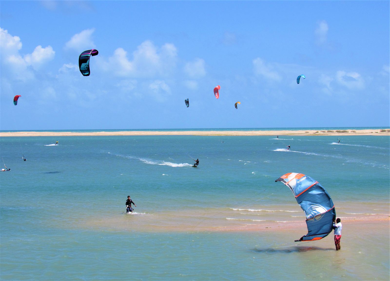 Kites navegando sobre el agua plana y turquesa de la costa de Ceará, con espacio libre alrededor